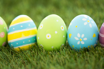 easter, holidays and tradition concept - row of colored eggs on artificial grass