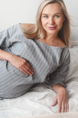 Happy pregnant woman lie on a bed at home