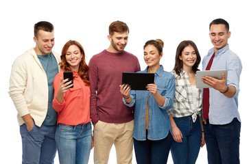 Obraz premium friendship and people concept - group of smiling friends with smartphone and tablet computers over white background