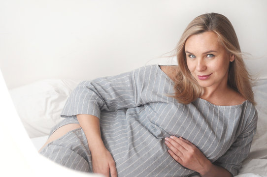 Happy pregnant woman lie on a bed at home