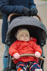 The little baby is sitting in the pram.