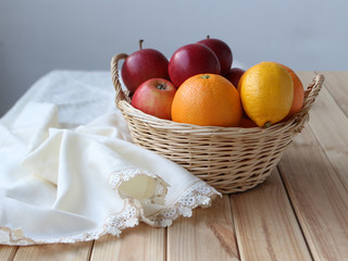 Wicker basket with fresh red apples stands on a light wooden background, on which lies a white napkin, the concept of food and health