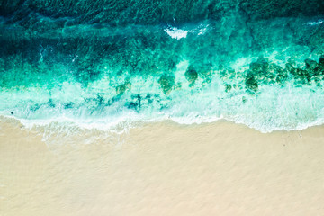Aerial over a tropical beach looking down at the surf and sand, Bali, Indonesia