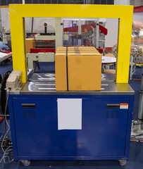 Production line of fully automatic carton / cardboard strapping band machine. Industrial warehouse