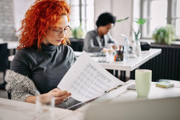 Young businesswoman reading financial reports while working in the office.