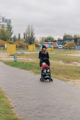 Obraz premium A woman walks in the park with a stroller and a small child near the lake.