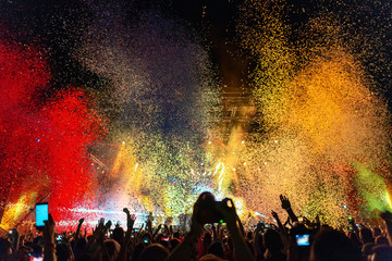 Fototapeta na wymiar Multi colored confetti above the crowd on music festival.