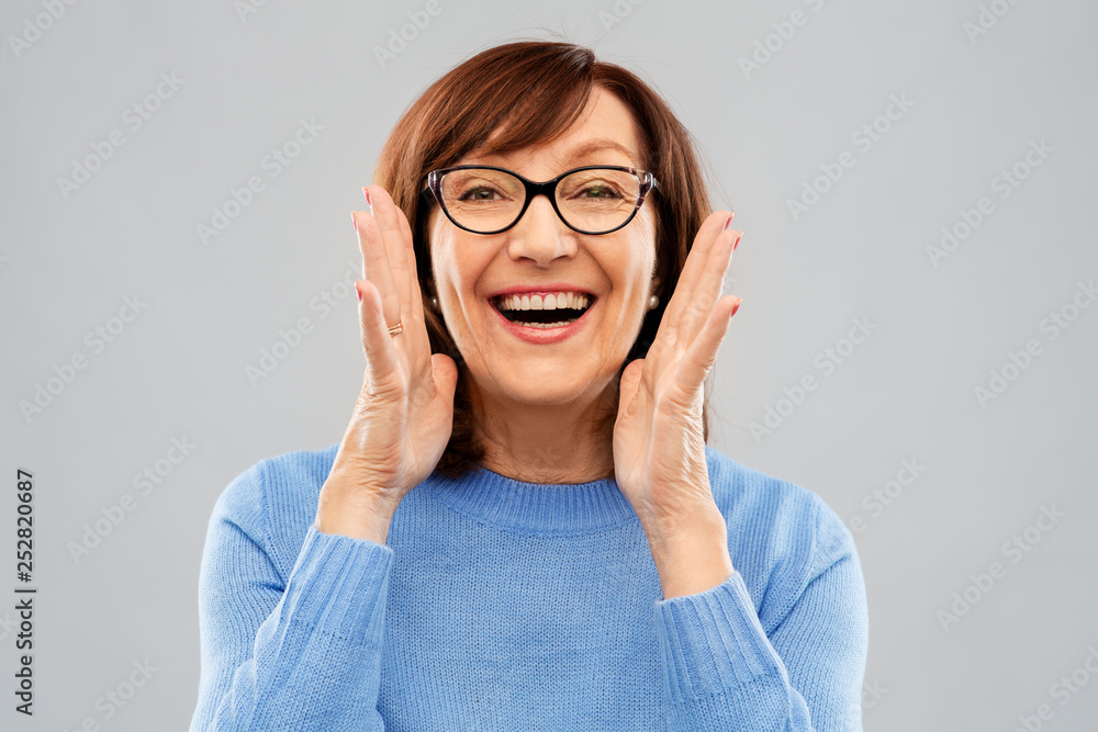 Sticker announcement and old people concept - smiling senior woman in glasses calling over grey background