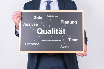 Manager mit einer Tafel zur Qualität und Schlagworten