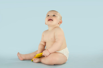 naked baby crawls on an isolated blue background and plays with the phone. The concept of education...