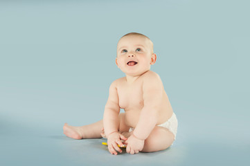 naked baby crawls on an isolated blue background and plays with the phone. The concept of education...