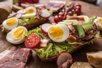 Baguette sandwich fresh vegetable dressing bacon panchetta tomatoes eggs and onion. Healthy nutrition breakfast or appetizer