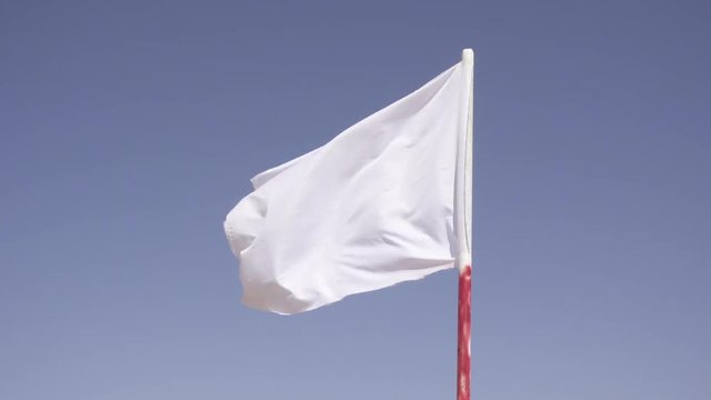 A white flag flutters in the middle of the desert.