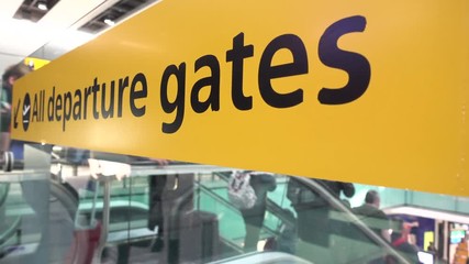 4K video clip of anonymous people traveling down an escalator at an airport terminal past a sign and towards departure gates