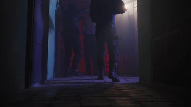Low angle shot of two guards leading a dangerous inmate through the halls, 4k