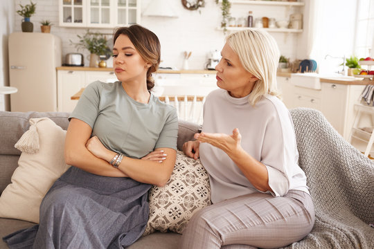 Annoyed Teen Girl Sitting On Sofa With Arms Crossed, Not Listening To Her Middle Aged Mother. 45 Year Old Woman Lecturing Her Stubborn Daughter. Relationship Problem, Age Gap And Different Generations