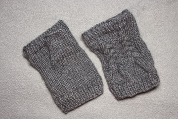 knitting women's gloves without fingers from gray wool yarn, auxiliary needle, braided pattern