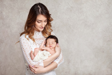 Pretty woman holding a newborn baby in her arms. Portrait of mother and little baby. Copy space