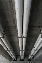 large industrial sewage and water pipes under a concrete bridge