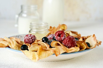 Homemade thin pancakes with berries, honey and milk for breakfast on a light background. Traditional cuisine. Pancake week. Shrovetide Maslenitsa Butter Week festival meal.