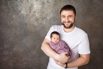 Smiling father holding his newborn baby  in  hands.  Concept of happy family. Copy space