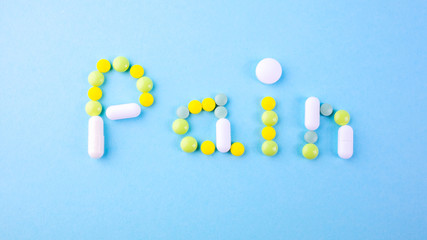 The word pain is lined with multi-colored pills on a blue background.
