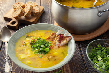 Fragrant yellow split pea soup  with smoked pork ribs  on a wooden table.