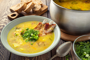 Fragrant yellow split pea soup  with smoked pork ribs  on a wooden table.