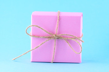 Pink gift box tied with string on a bright blue background, minimalism, parcel.