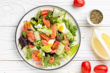 Salad with salmon, egg and vegetables (cherry tomatoes, cucumber, lettuce), delicious light lunch, healthy food