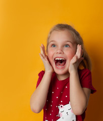 excited screaming young girl standing isolated over yellow background.