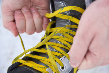 A man tying skates in the snow in winter