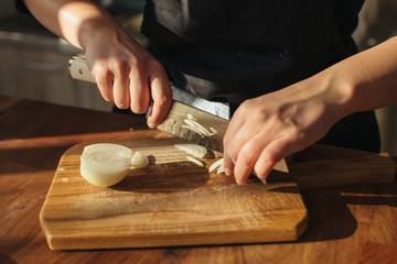 Obraz na płótnie Canvas Female chef chopping onions on a wooden board