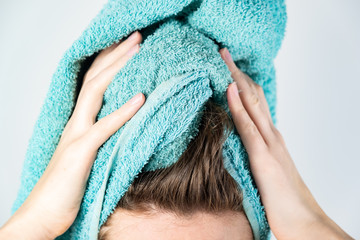 Female drying her hair with towel. Close-up of woman using bath towel for manual hair drying