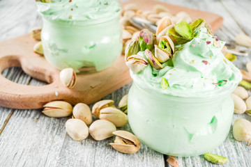 Vegan trend food. Homemade pistachio yogurt ice cream with fresh pistachios. On a white wooden table,