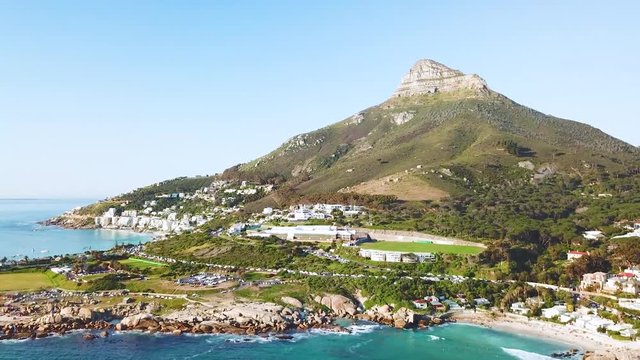 Aerial moving along the shoreline of Camps Bay, Cape Town, South Africa, with Lion's Head mountain background.