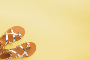 Golden colored shoes on pastel yellow background, minimalistic summer fashion concept. Top view, selective focus