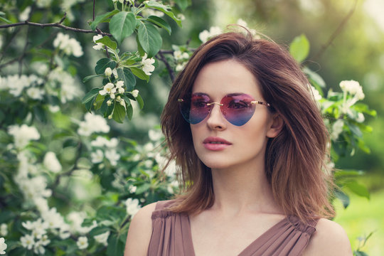 Young beautiful woman in sunglasses outdoors. Cute girl with brown layered hair,  spring portrait