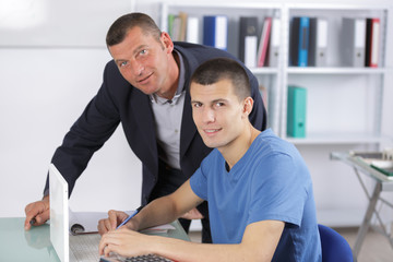 computer teacher assisting a student in classroom