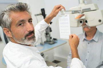 Fototapeta na wymiar ophthalmologist holding text for patient to read through phoropter