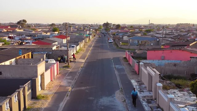 Aerial over street scene in township of South Africa, with people walking on streets.
