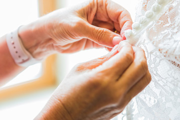 Obraz premium Bridesmaid helping bride fasten corset and getting her dress, preparing bride in morning for the wedding day