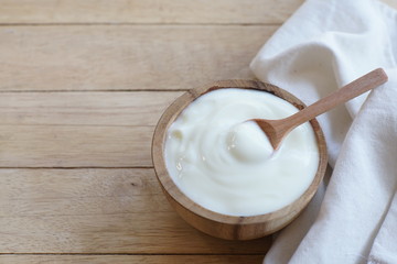 Natural homemade plain organic yogurt in wood bowl on wood texture background