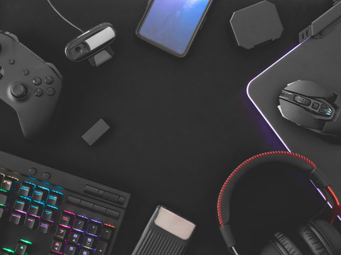 streaming games concept, top view a gaming gear, mouse, Webcams, keyboard, joystick, headset and mouse pad on black table background.