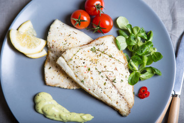 Fried fillet dorado (fish) with tomatoes, lemon and corn salad. Selective focus, close-up.