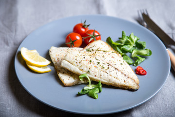 Fried fillet dorado (fish) with tomatoes, lemon and corn salad. Selective focus, close-up.