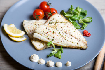 Fried fillet dorado (fish) with tomatoes, lemon and corn salad. Selective focus, close-up.
