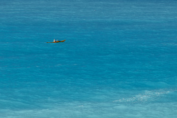 A man canoeing in  turquoise sea, view from faraway, holidays outdoor sport activity. Copy space.