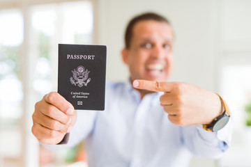 Middle age man holding holding passport of United States very happy pointing with hand and finger