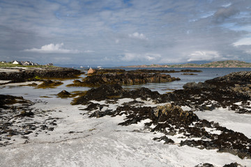 White sand and rocks on the shore of Isle of Iona with Isle of Mull on other side of Sound of Iona Inner Hebrides Scotland UK